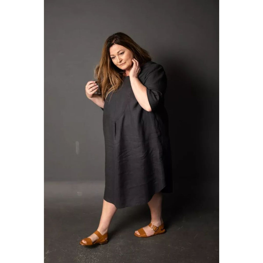Woman wearing a dark gray dress against a plain background