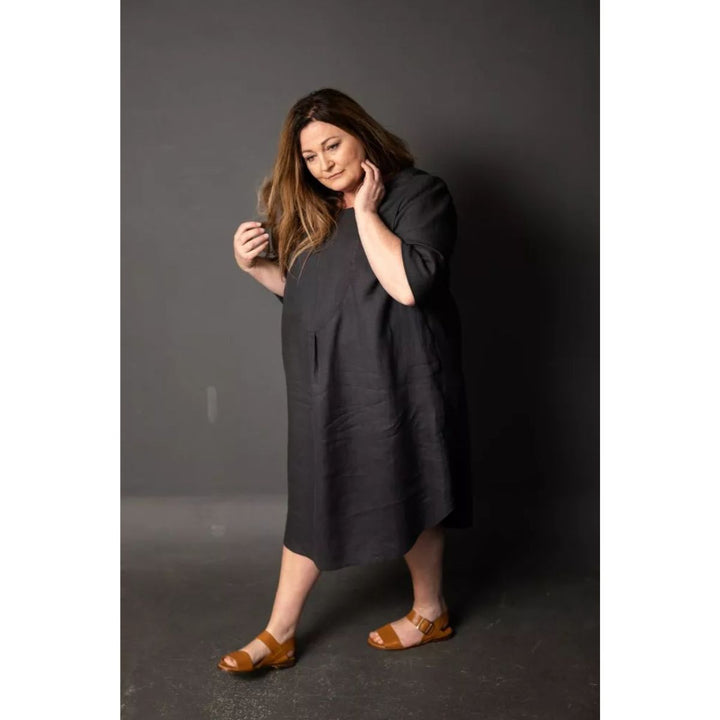 Woman wearing a dark gray dress against a plain background
