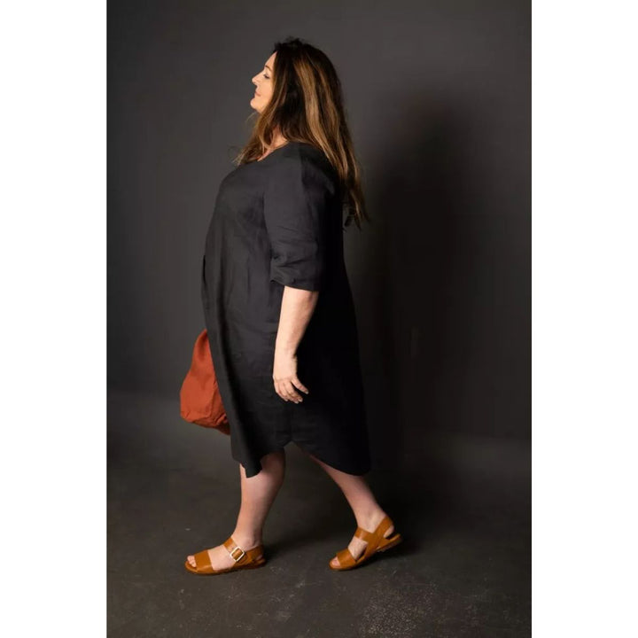 Woman wearing a black dress with a red bag against a dark background