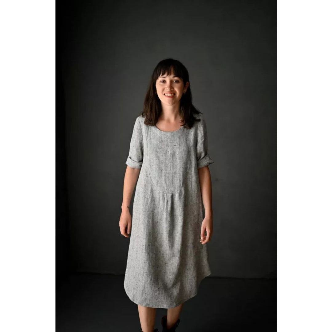 Woman wearing a gray dress against a dark background