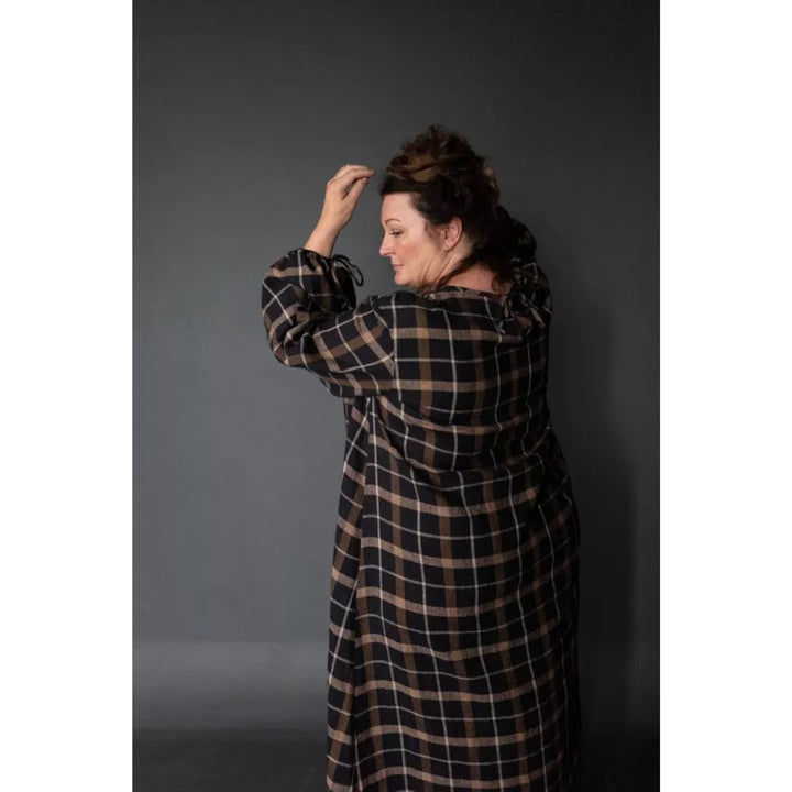 Person wearing a plaid dress against a gray background