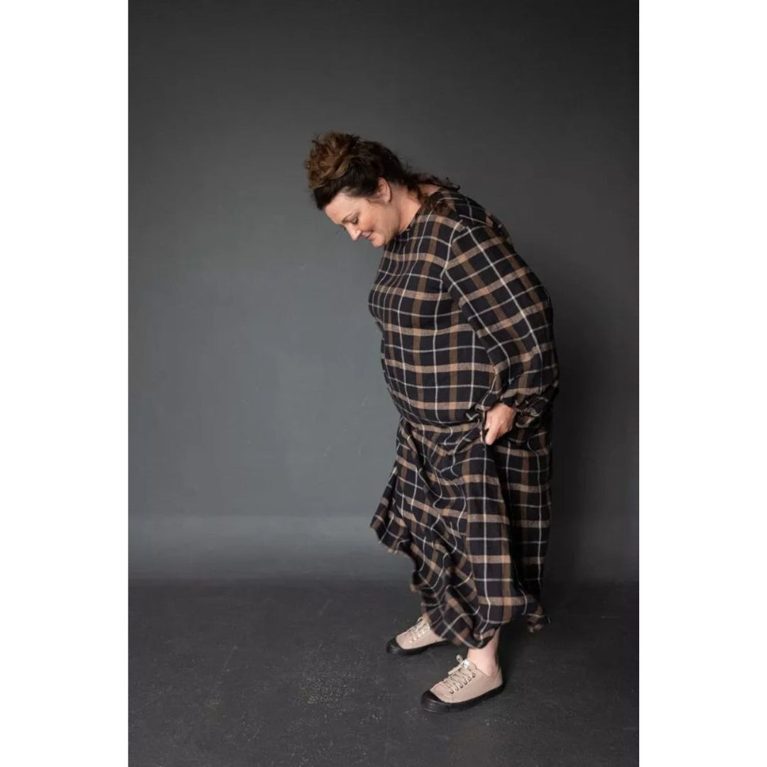 Person wearing a plaid dress against a gray background