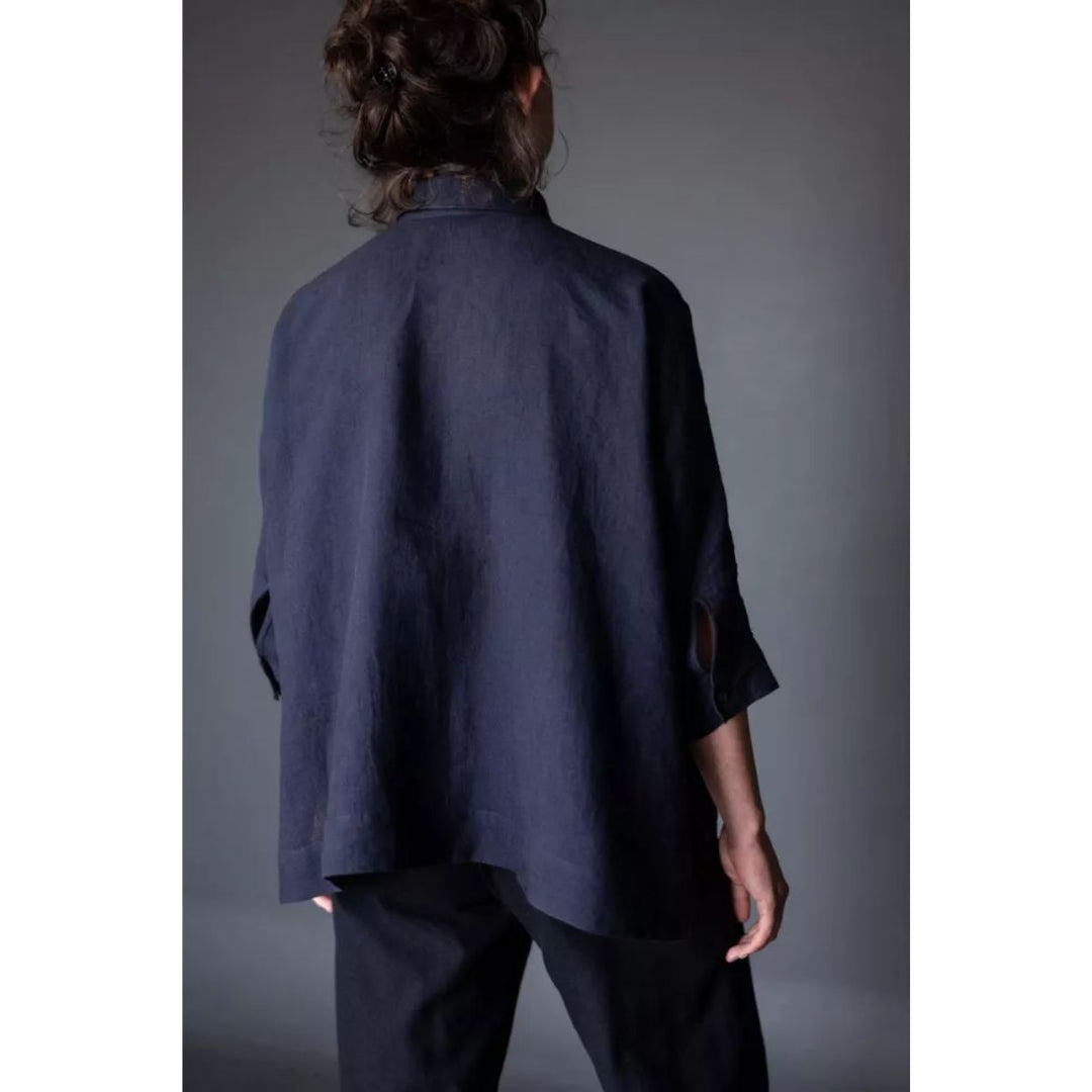 Person wearing a dark blue shirt and pants against a gray background