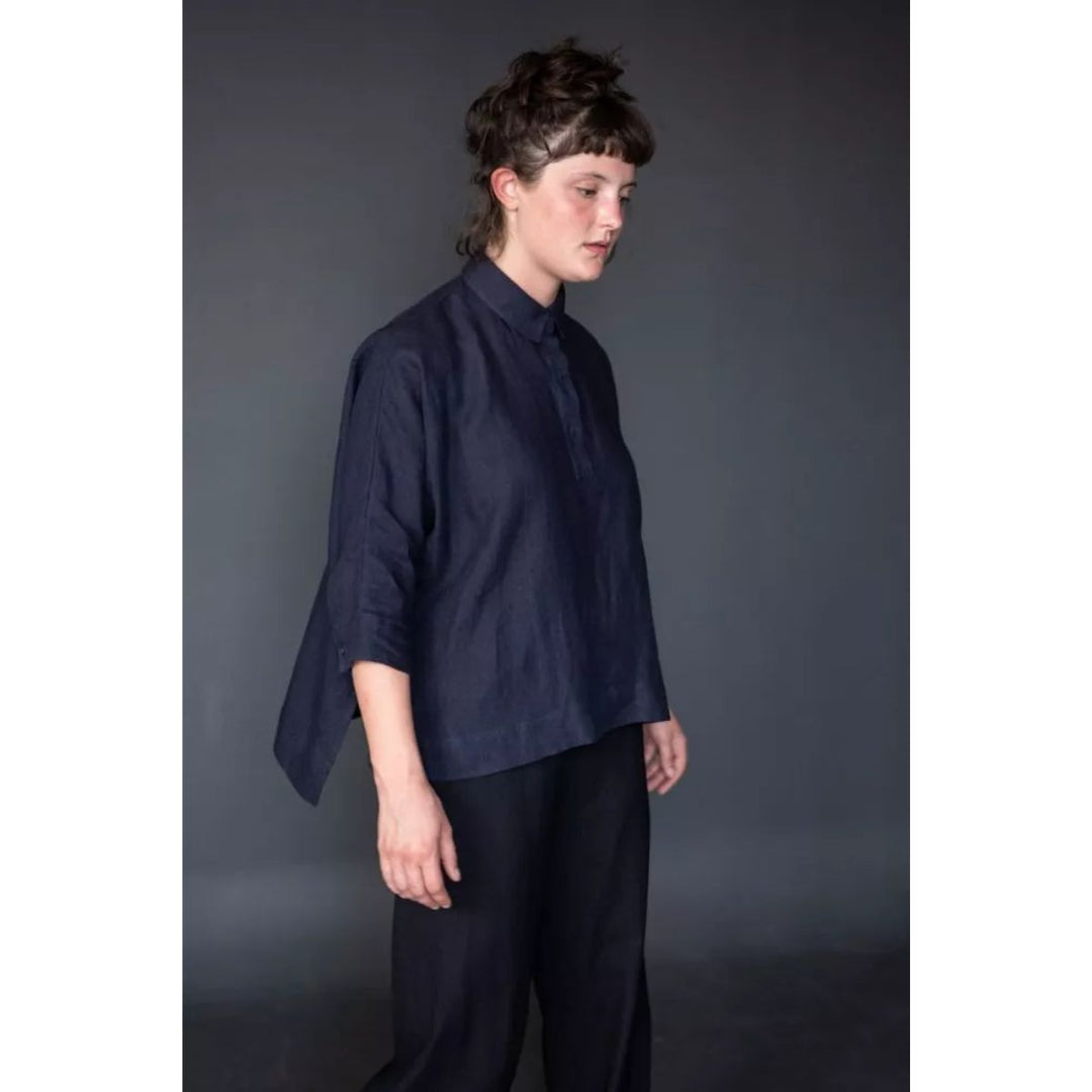 Person wearing a dark blue shirt and pants against a gray background