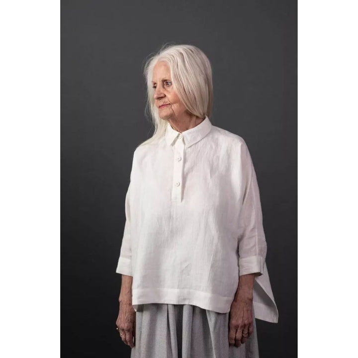 Woman wearing a white shirt against a dark background