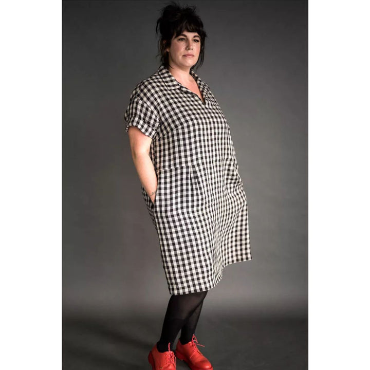 Person wearing a black and white checkered dress with red shoes on a gray background