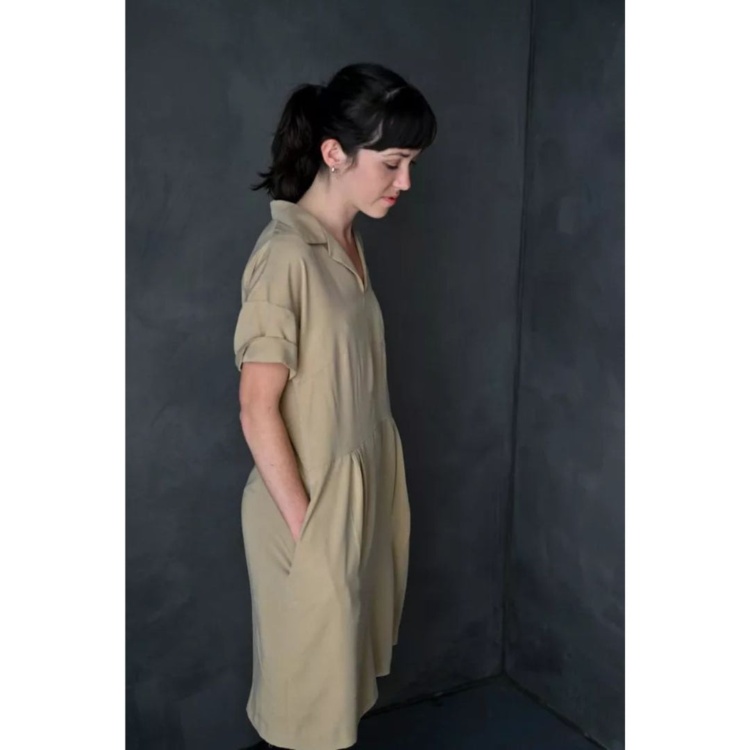 Woman wearing a beige dress against a dark background