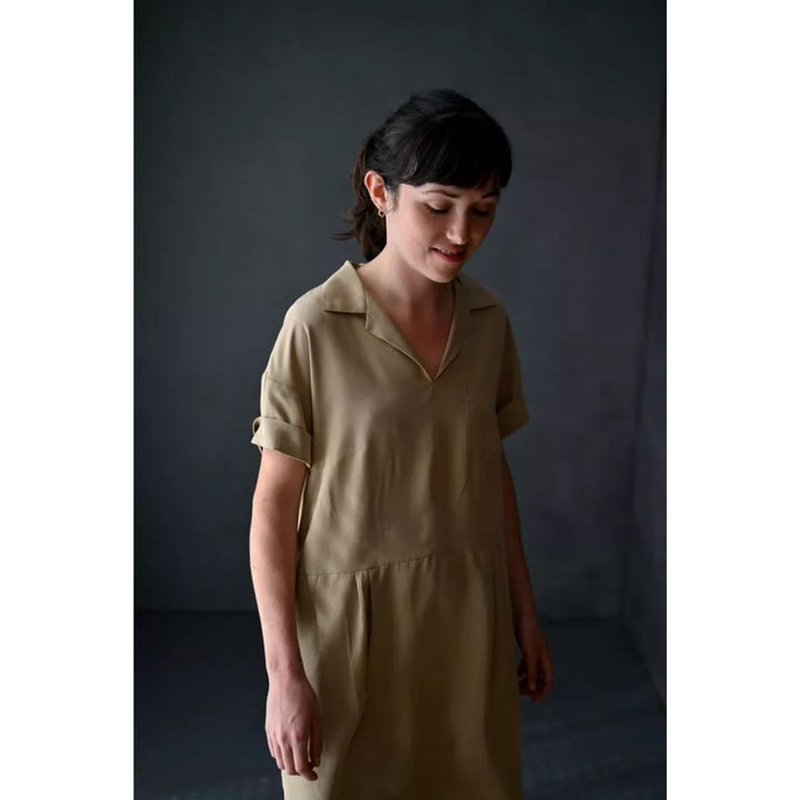 Woman wearing a beige dress against a dark background