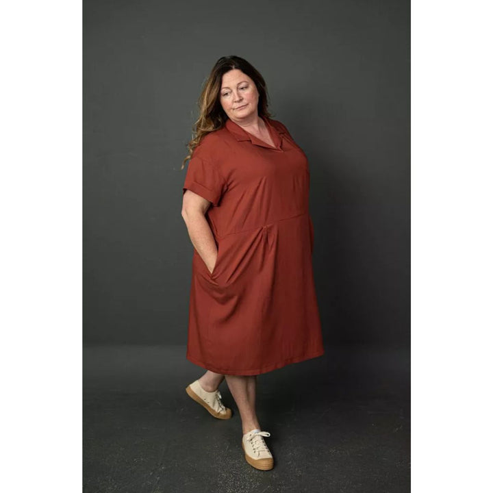 Woman wearing a rust-colored dress against a dark background