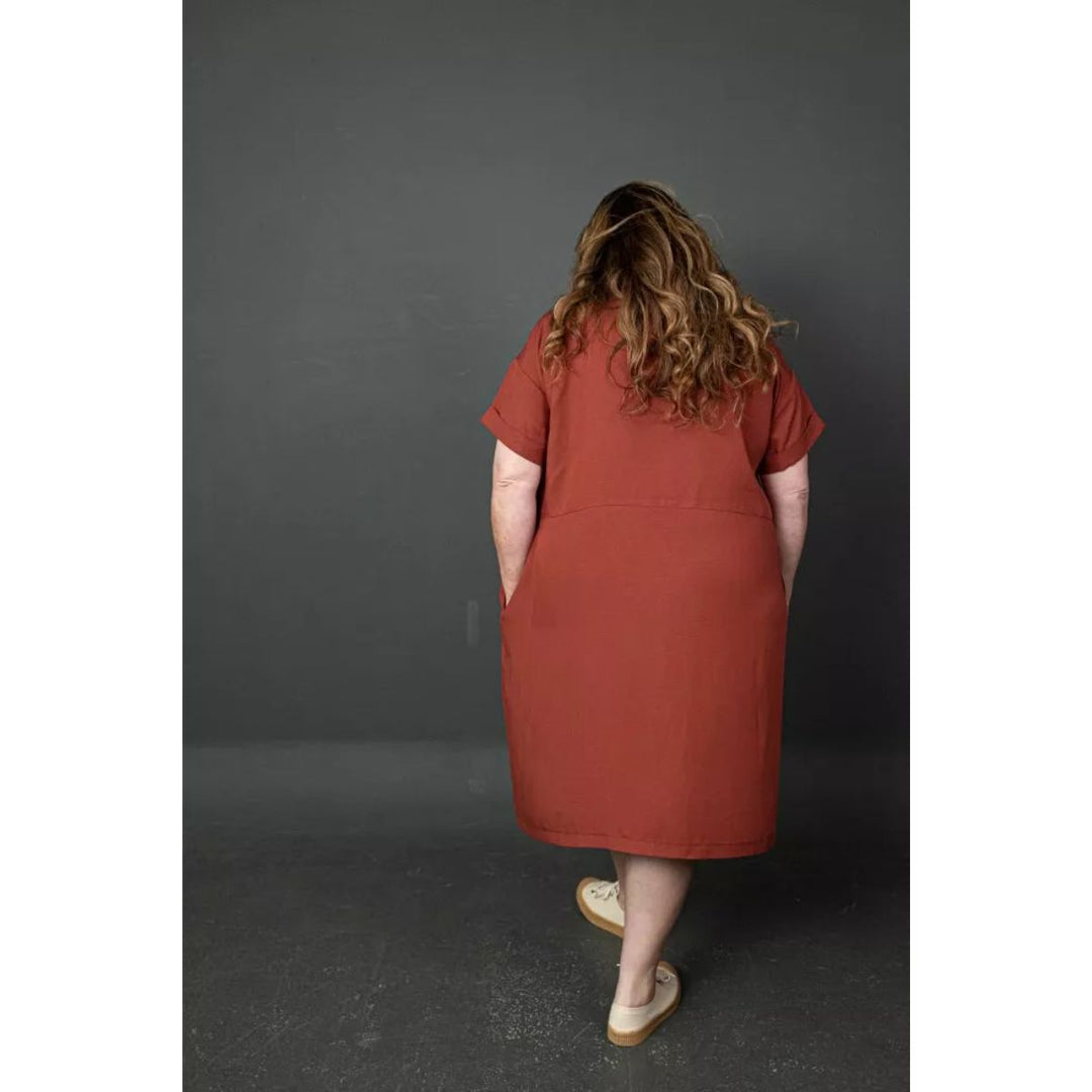 Person wearing a rust-colored dress against a dark gray background