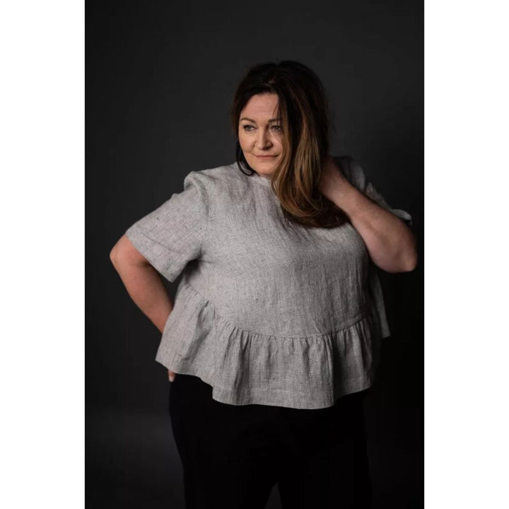 Woman wearing a gray linen top against a dark background