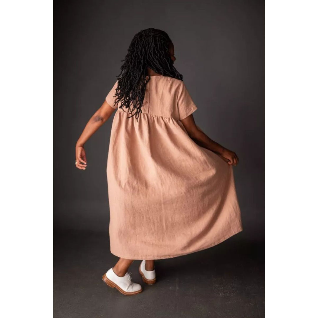 Woman wearing a long beige dress against a dark background