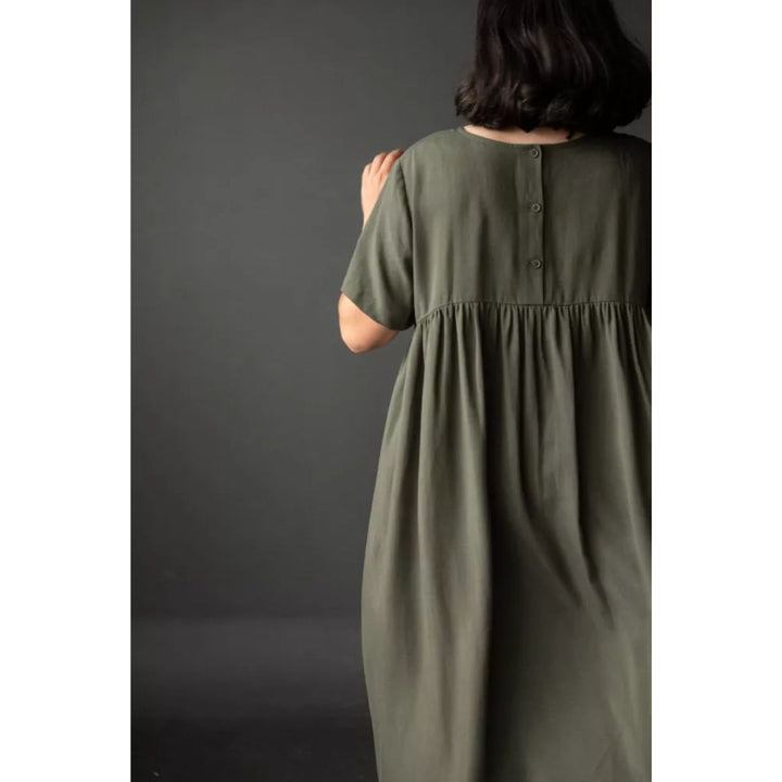 Person wearing a green dress against a dark background