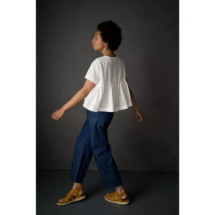 Person wearing a white top and blue pants against a dark background