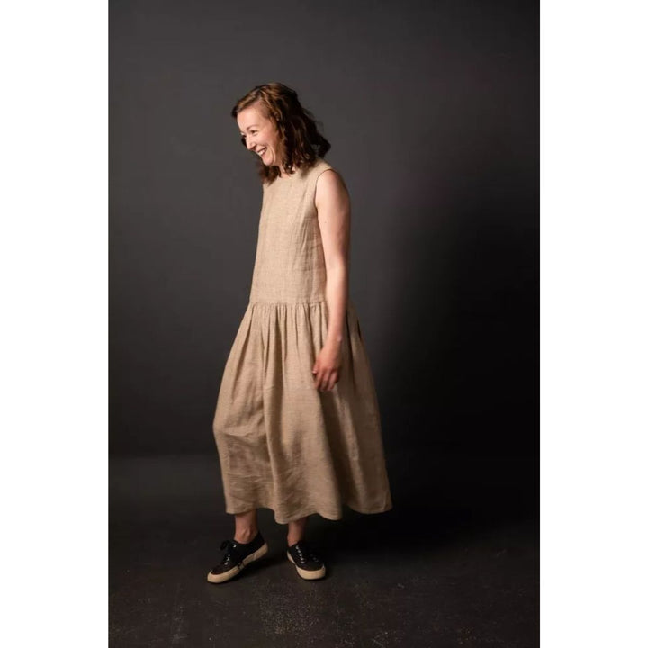 Woman wearing a beige dress against a dark background