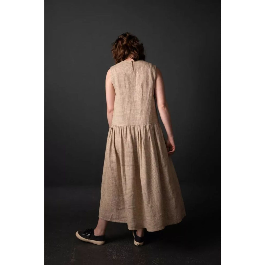 Woman wearing a beige dress against a dark background
