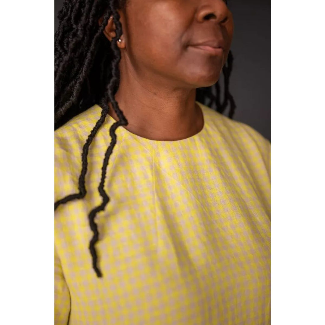 Person wearing a yellow top with a plain background