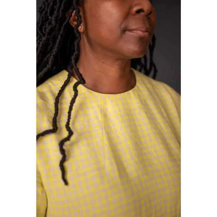 Person wearing a yellow top with a plain background