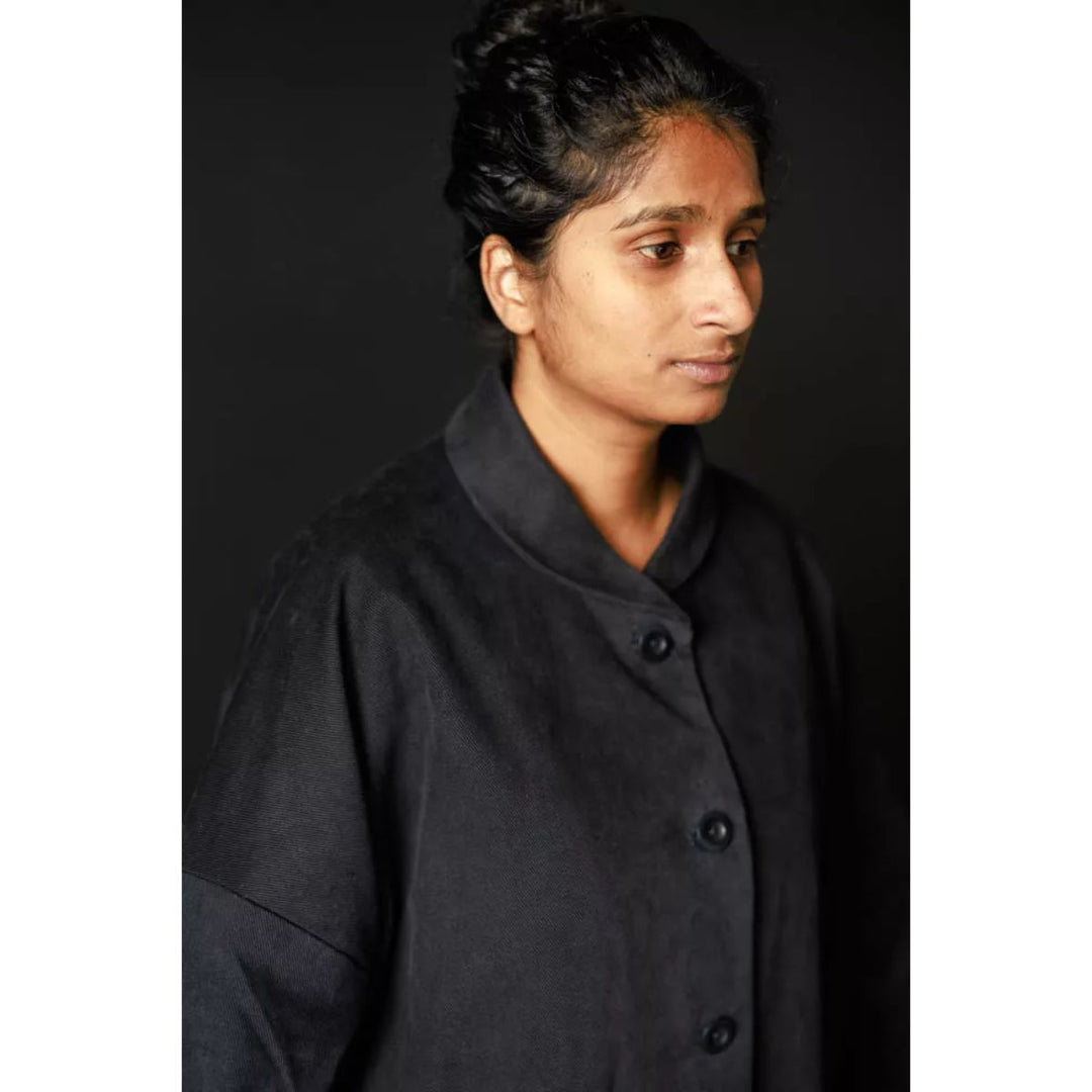Person wearing a black coat against a dark background