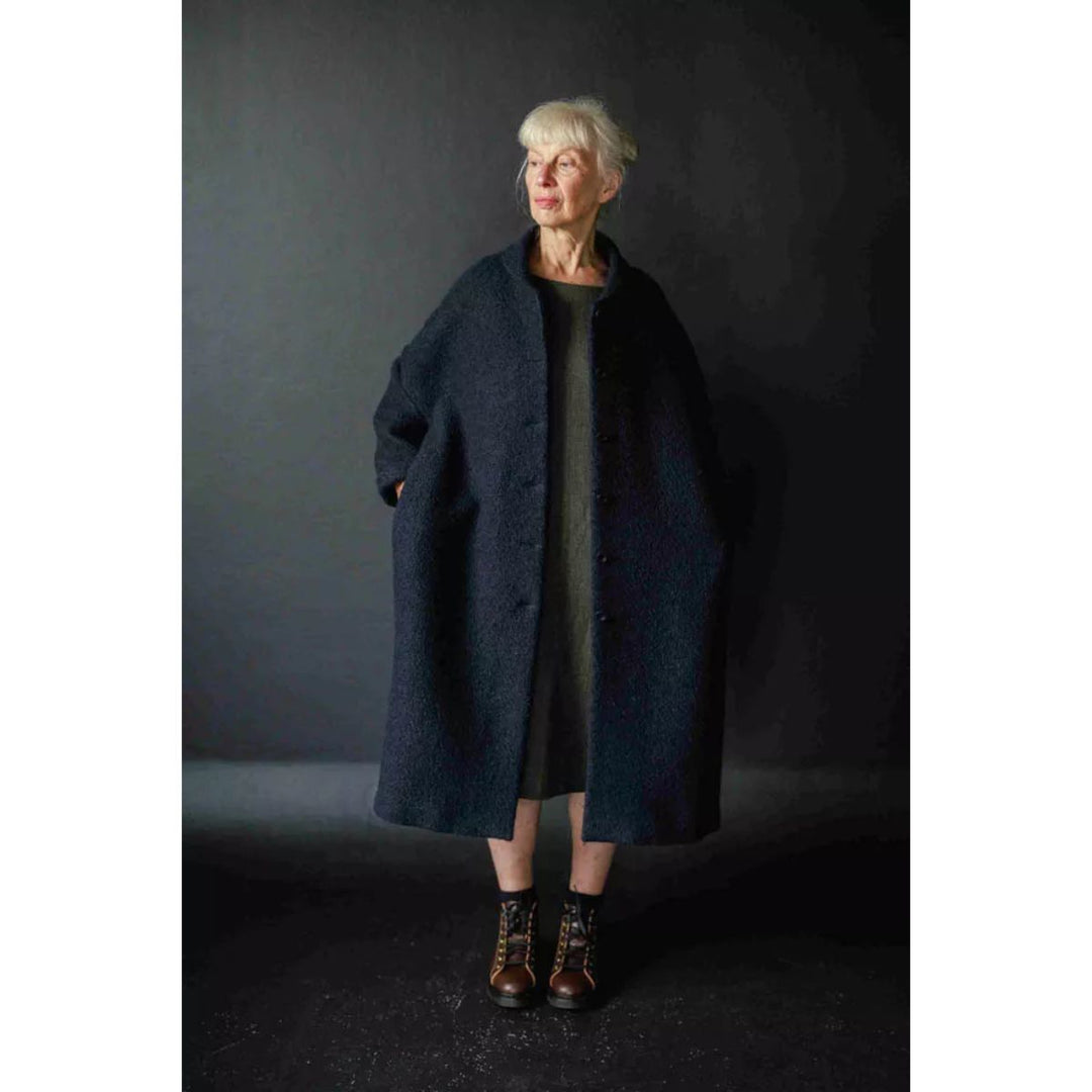 Woman wearing a dark coat against a dark background