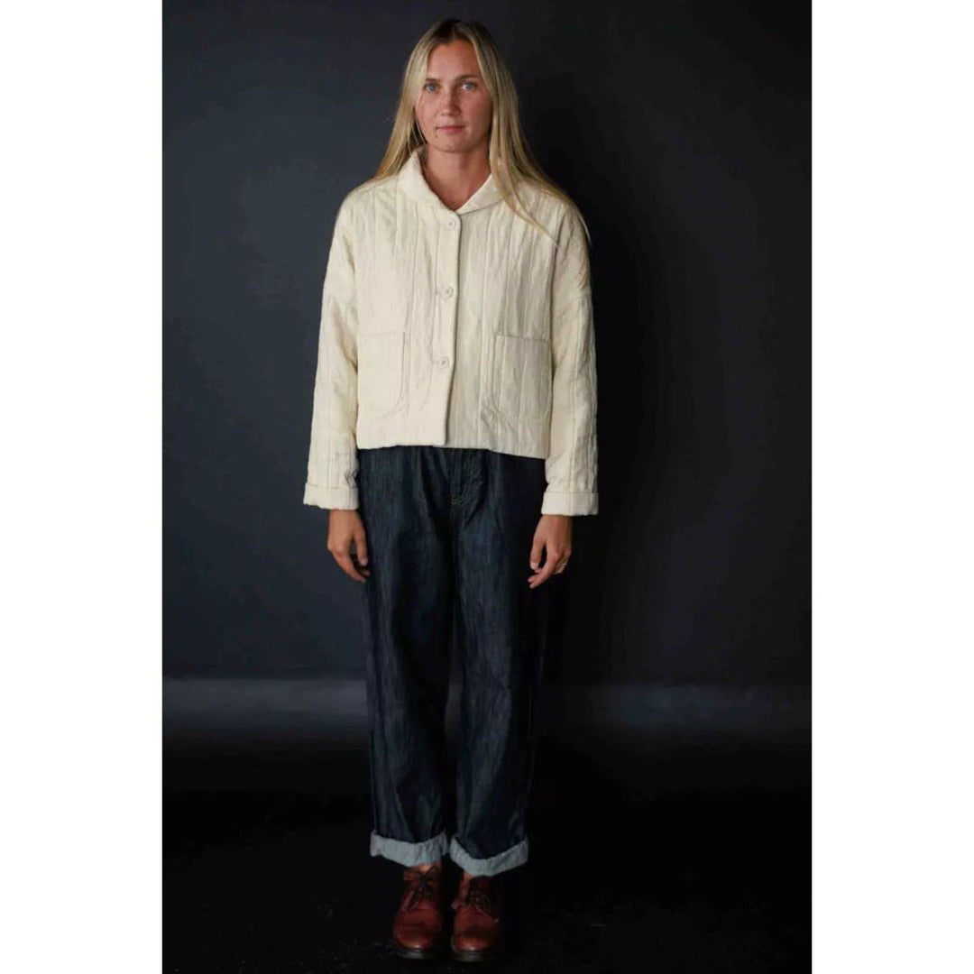 Person wearing a light-colored shirt and dark pants against a black background