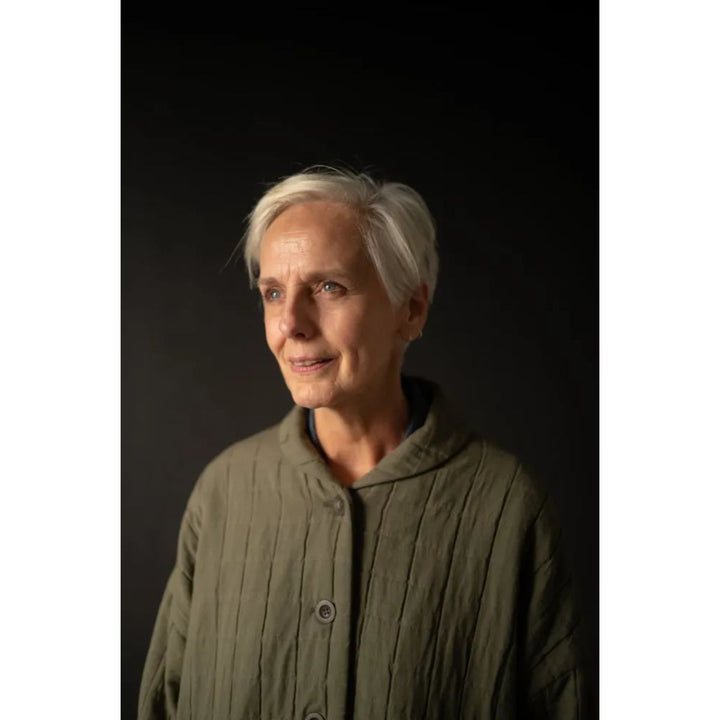 Person wearing a green jacket against a black background