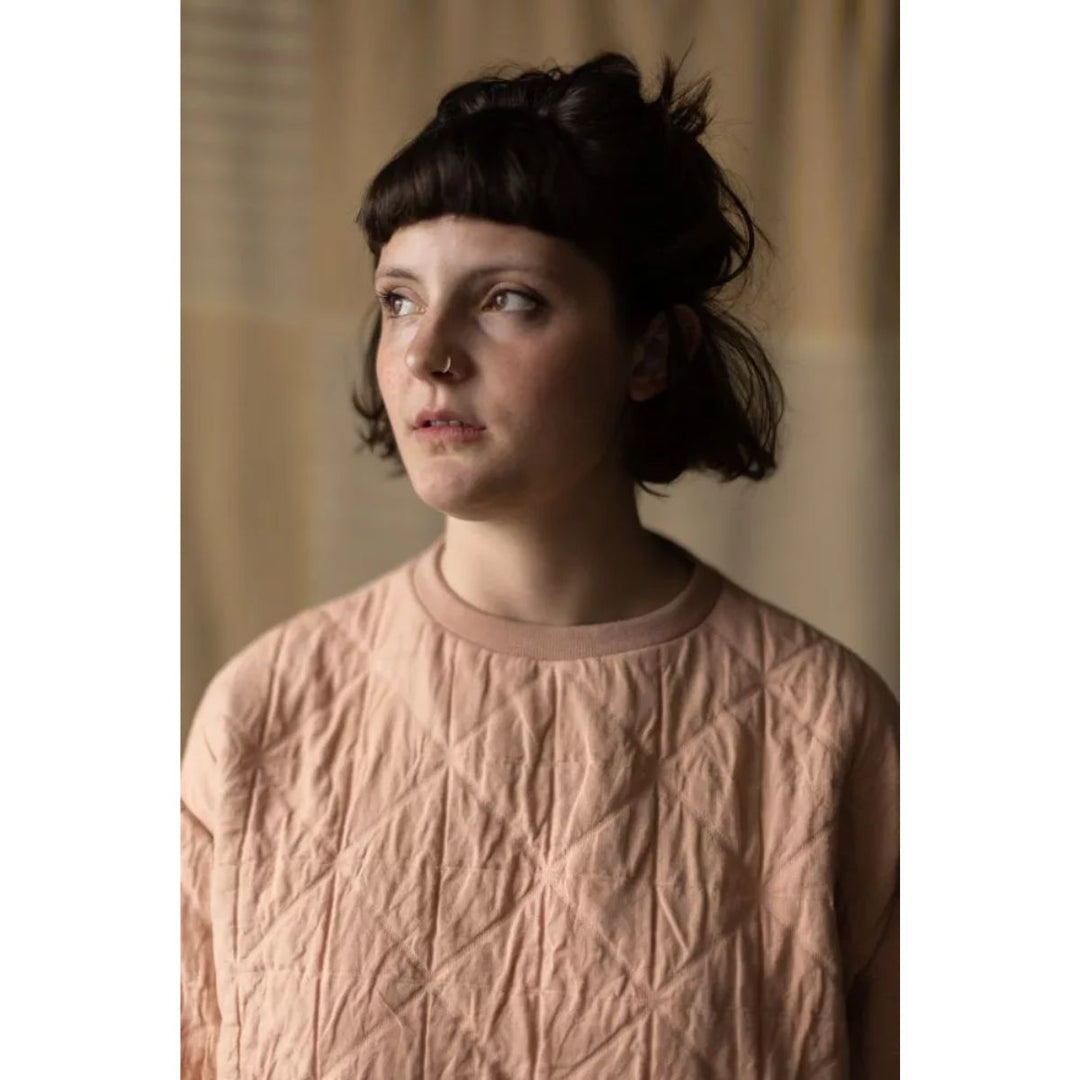 Woman wearing a textured pink sweater against a neutral background