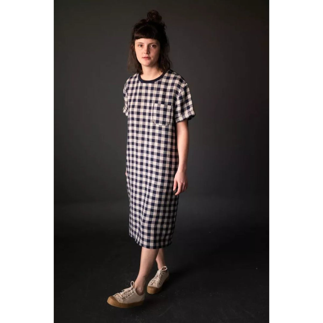 Person wearing a black and white checkered dress against a dark background