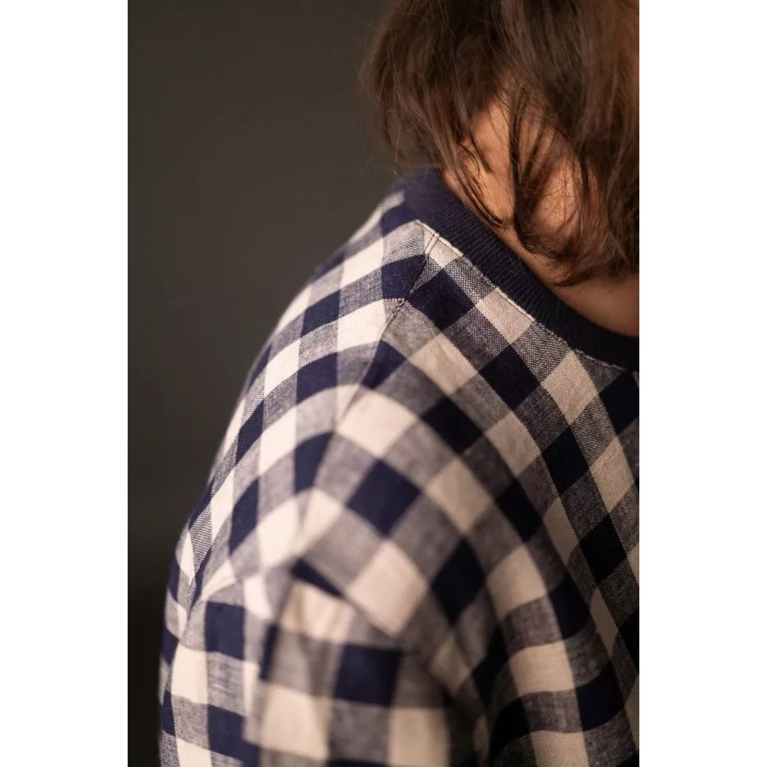 Person wearing a blue and white checkered shirt with a blurred background