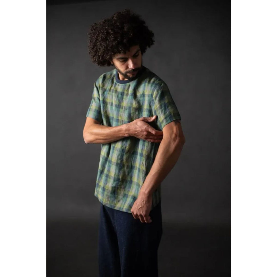 Man wearing a green and blue plaid shirt against a dark background