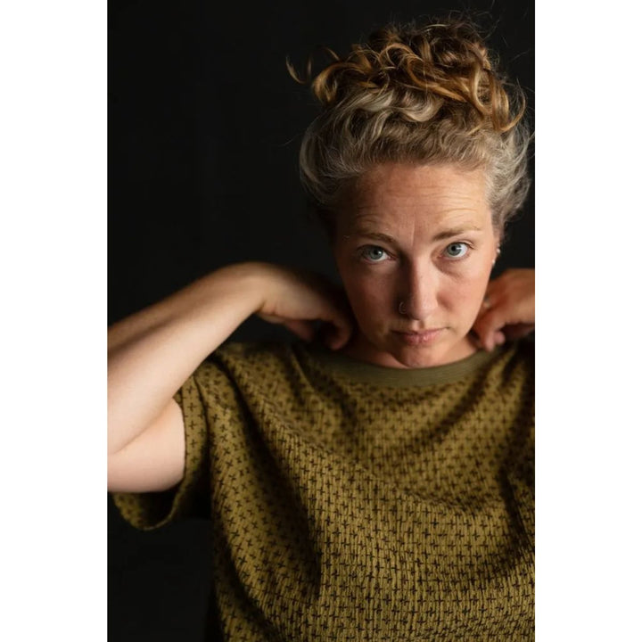 Woman wearing a green knitted sweater against a dark background