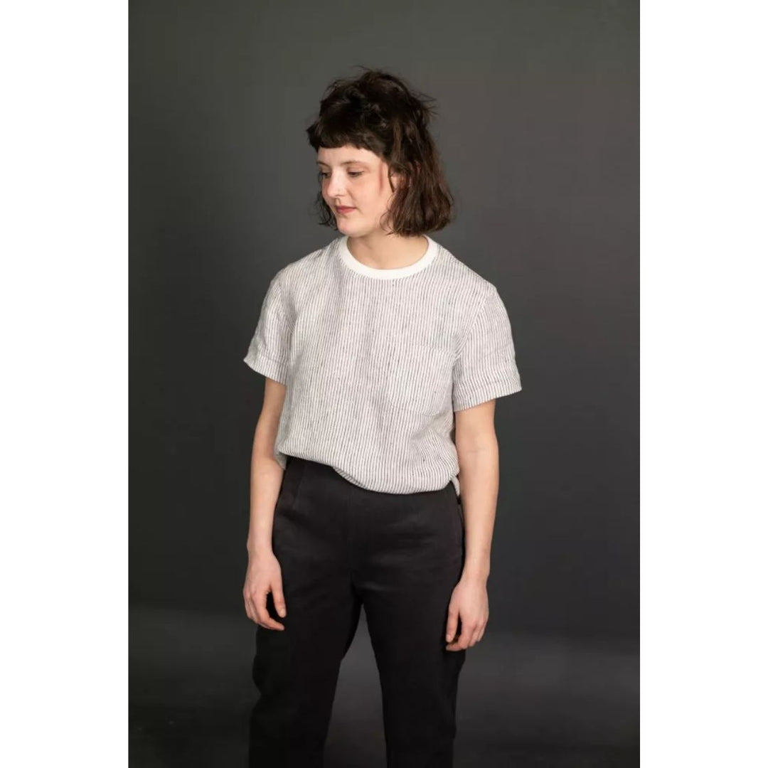 Person wearing a light gray textured shirt and black pants against a dark background