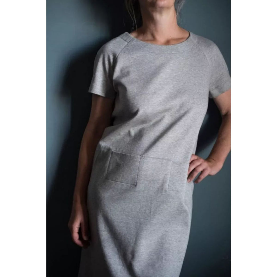 Person wearing a gray dress against a dark background