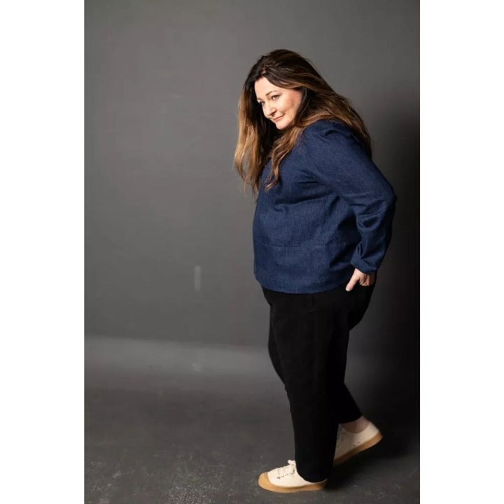 Woman wearing a blue jacket and black pants against a gray background