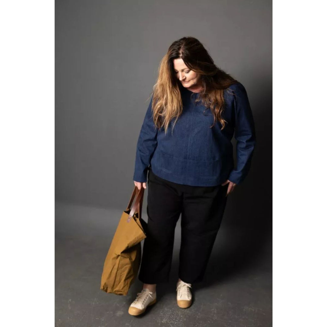 Woman holding a brown bag against a gray background