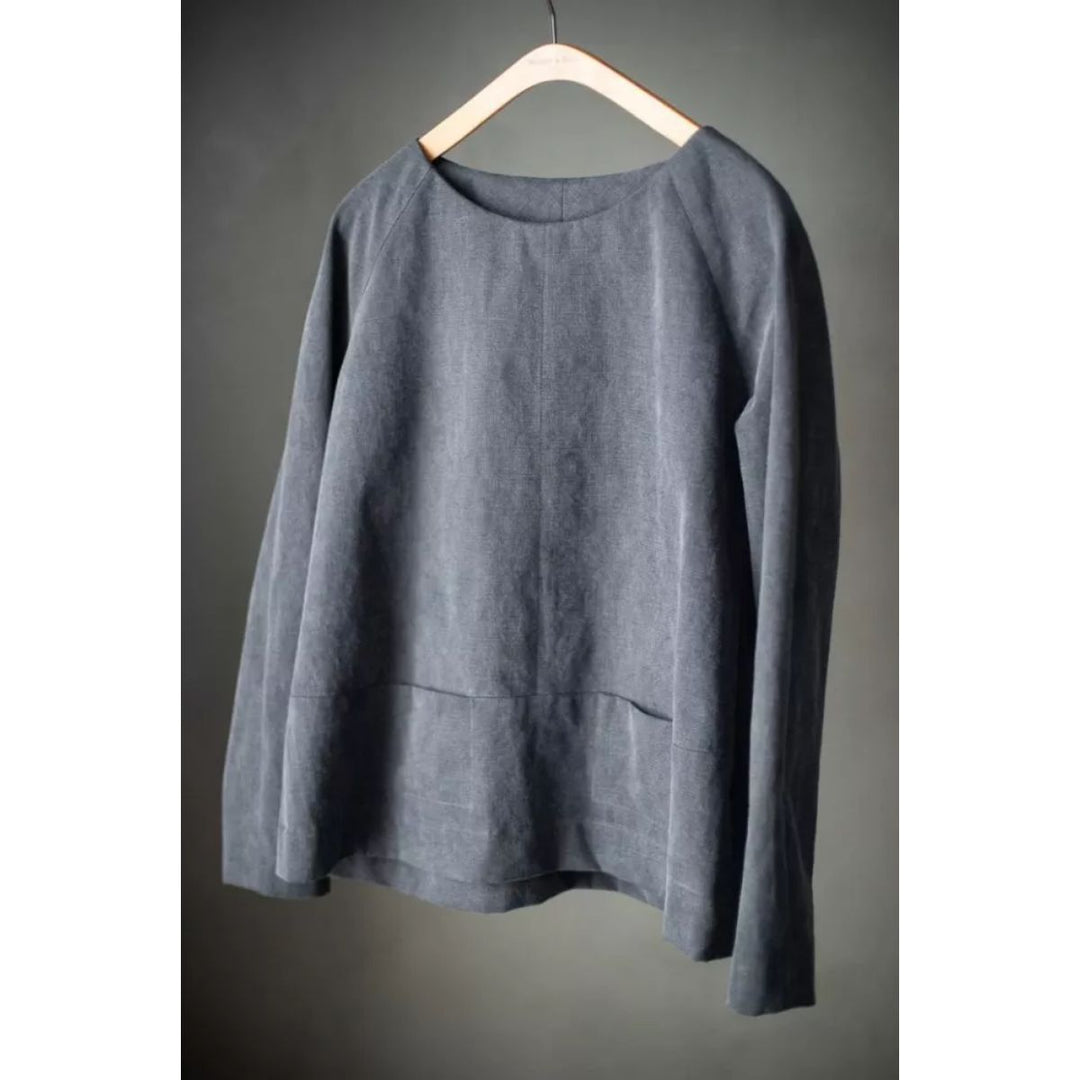 Gray long-sleeve shirt on a wooden hanger against a gray background