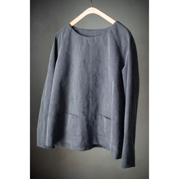 Gray long-sleeve shirt on a wooden hanger against a gray background