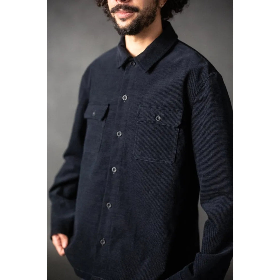 Man wearing a dark blue button-up shirt against a gray background