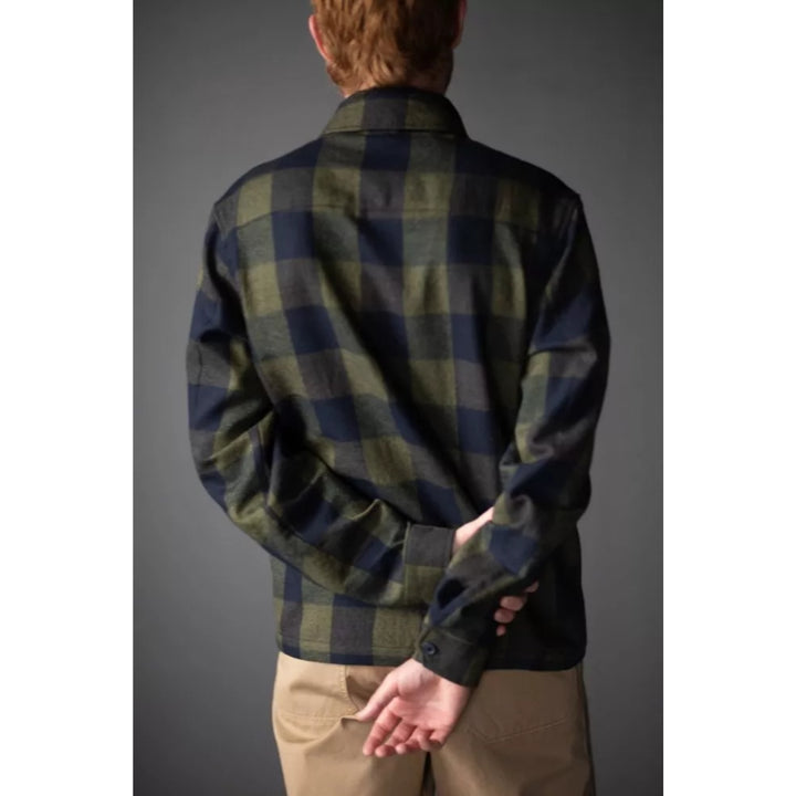 Person wearing a green and navy plaid shirt against a gray background