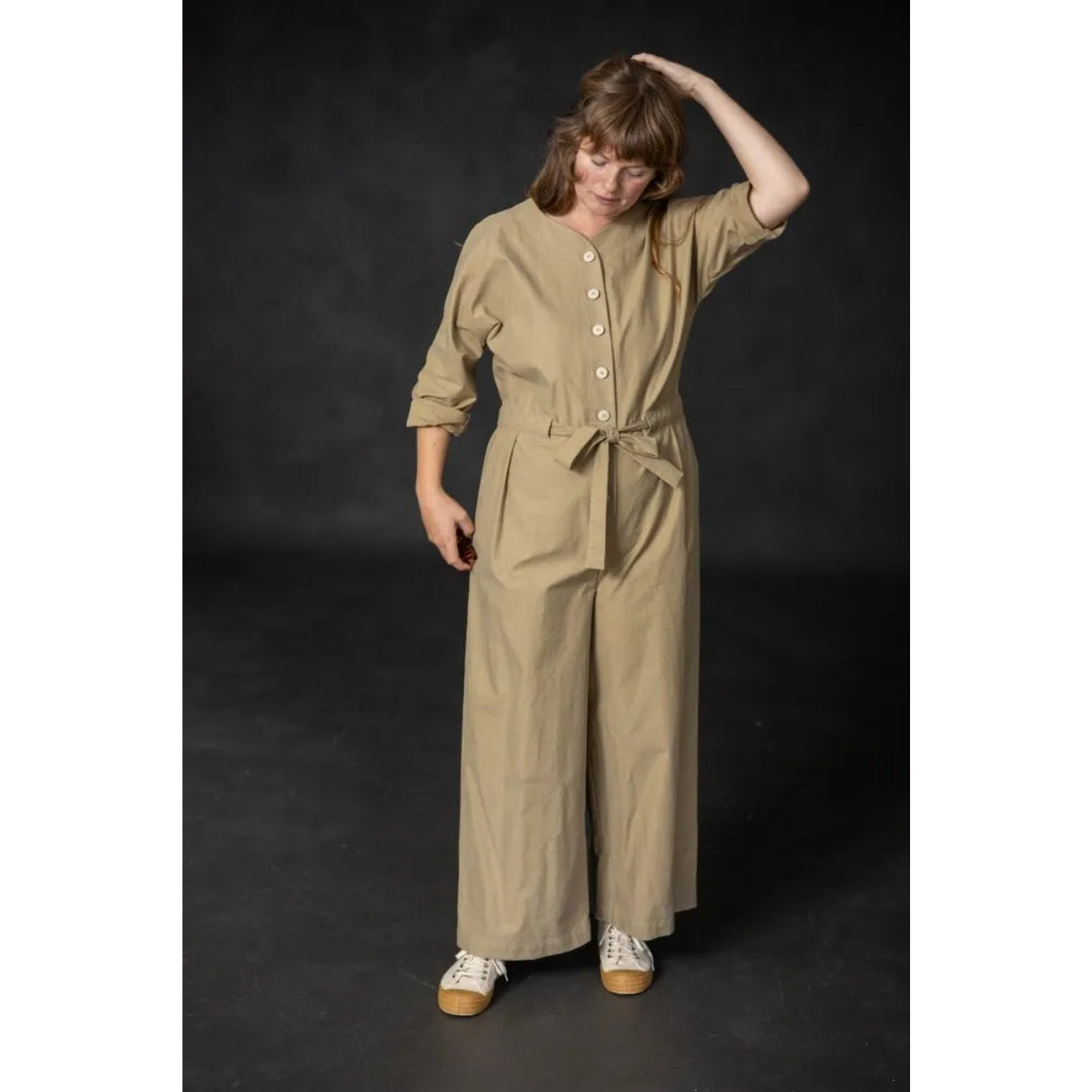 Woman wearing a beige jumpsuit against a dark background