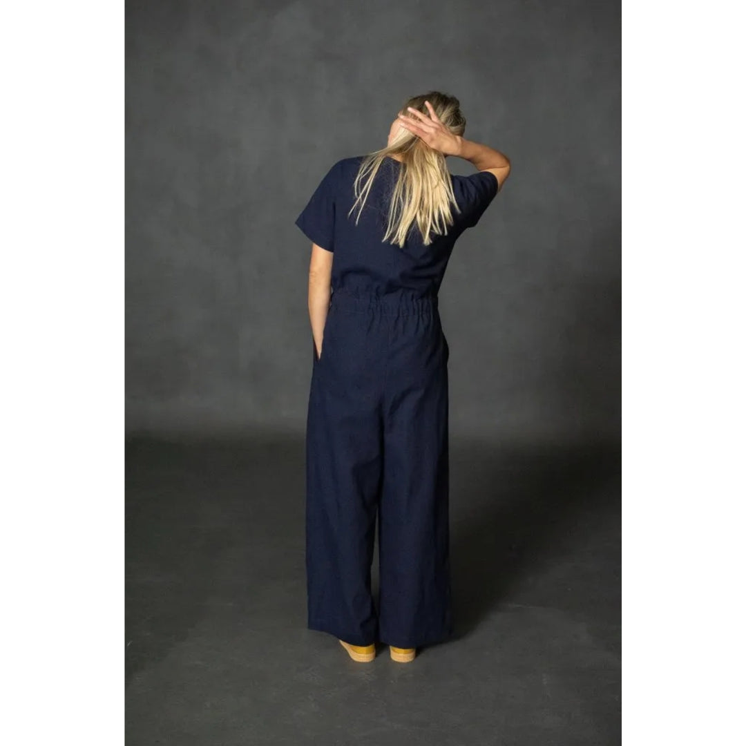 Person wearing a navy blue jumpsuit against a dark gray background