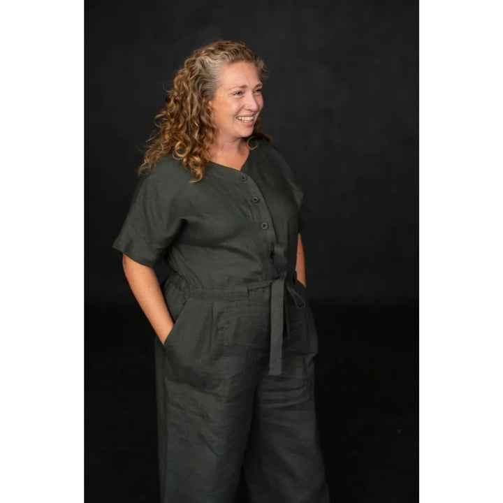 Woman wearing a dark green jumpsuit against a black background