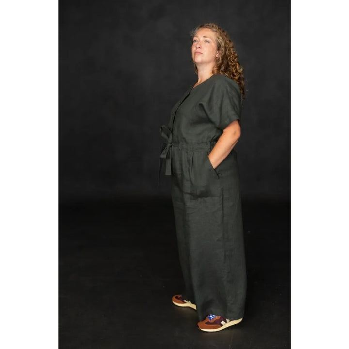 Woman wearing a dark green jumpsuit against a black background