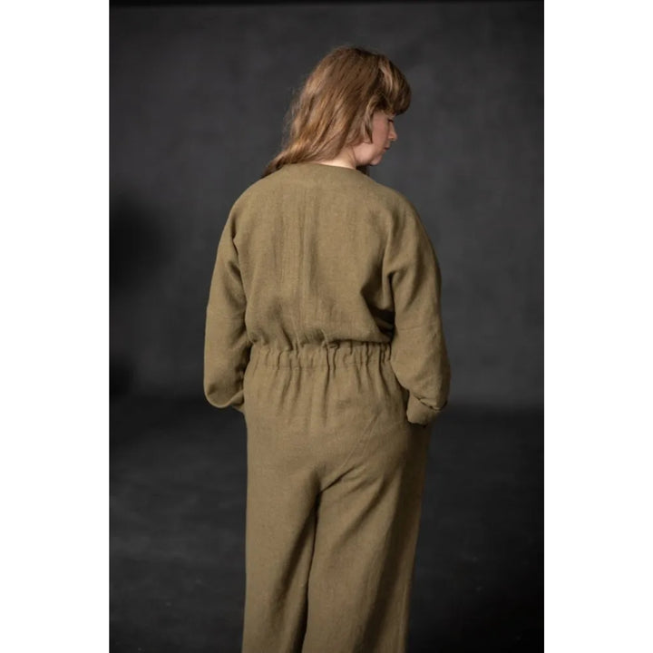 Person wearing a green jumpsuit against a dark background