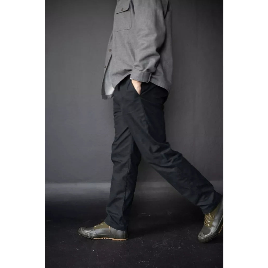 Person wearing a gray shirt and black pants against a dark background