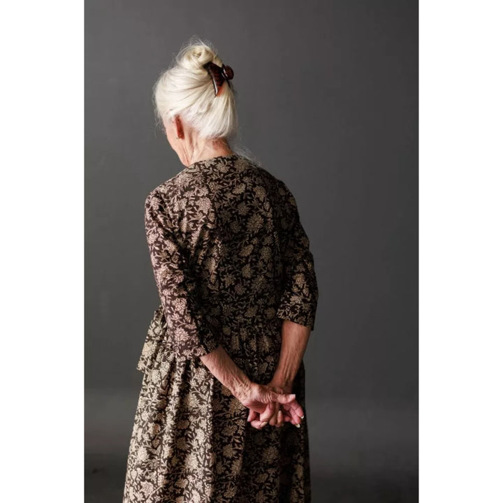 Person wearing a patterned dress against a plain background