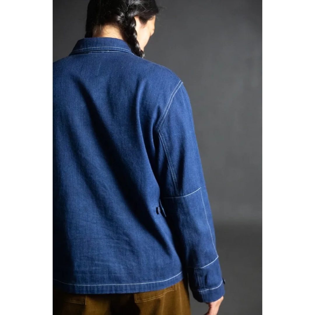 Person wearing a blue denim jacket against a gray background