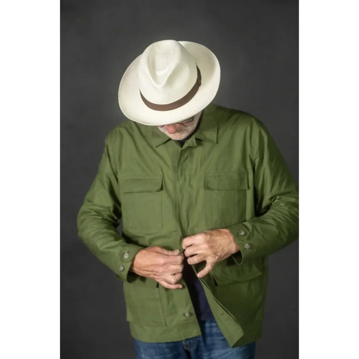 Man wearing a green shirt and white hat against a dark background