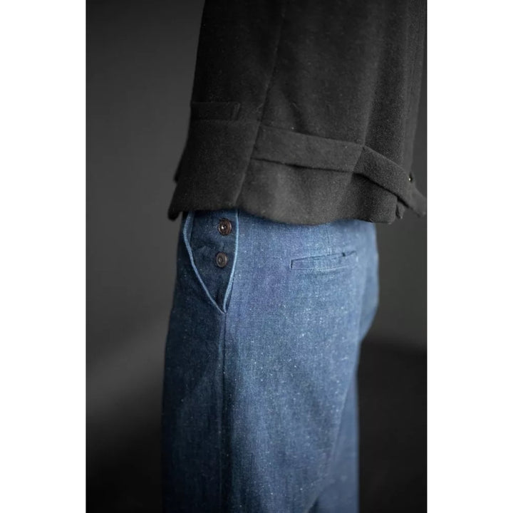 Close-up of blue jeans with a dark gray jacket on a plain background