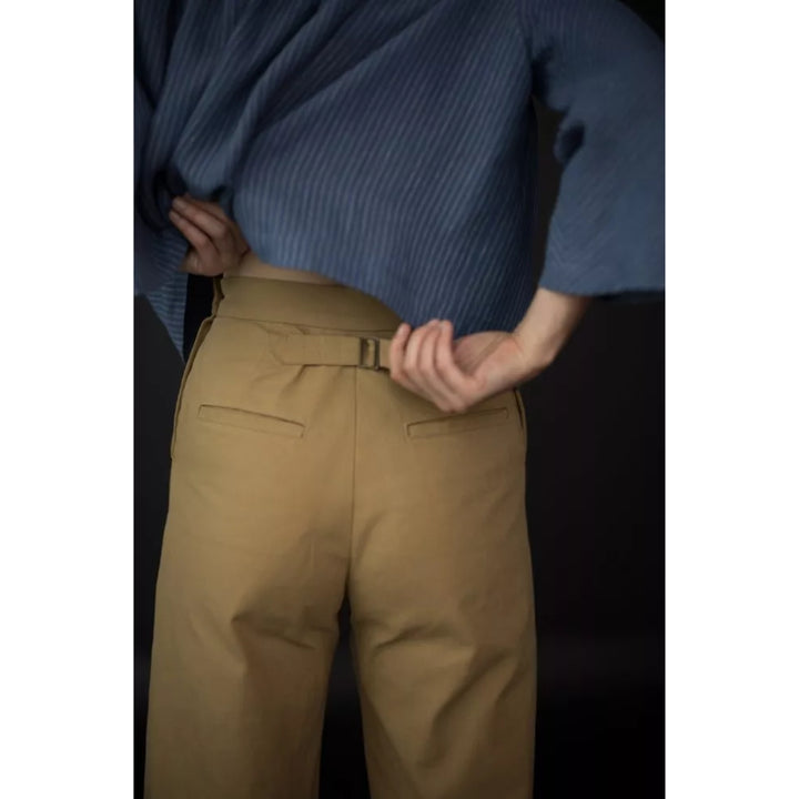 Person wearing a blue ribbed sweater and beige pants with a blurred background